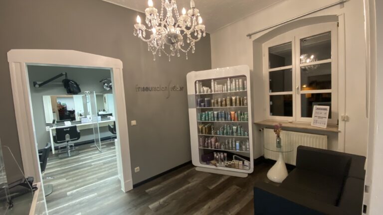 Blick durch den Salon mit Kronleuchter und Pflegeprodukten