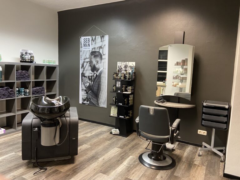 Stylingplatz mit großem Spiegel und dunklem Friseurstuhl im Salon Röder