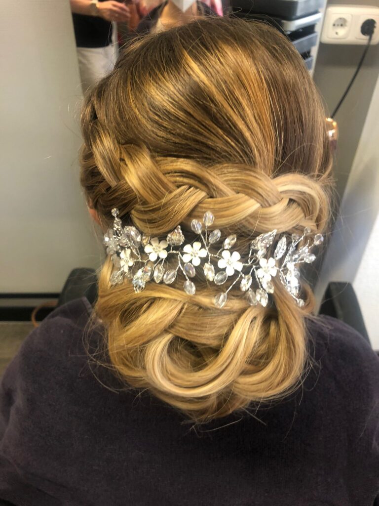 Kunstvoll gesteckte blonde Hochsteckfrisur mit floralem Haarschmuck aus dem Salon Röder